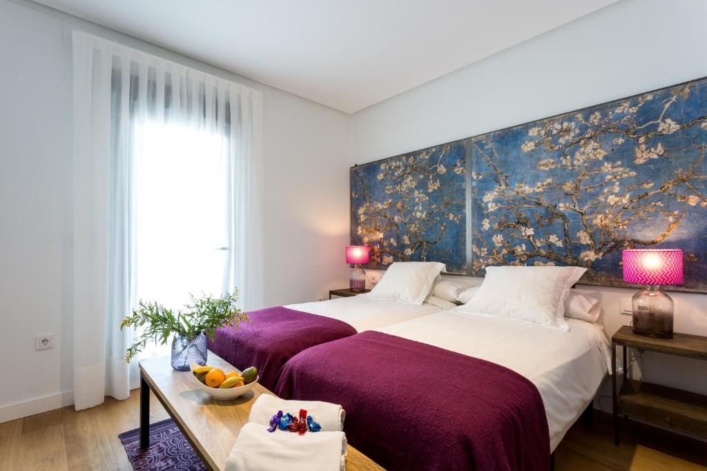 een slaapkamer met een groot bed en een schilderij aan de muur bij Apartamentos RG Plaza de España in Sevilla