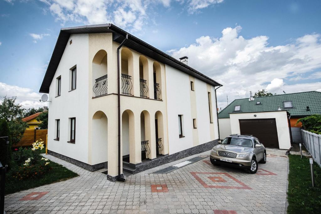 un coche aparcado frente a un edificio blanco en Cottage Prestige in City Centre & dom4, en Grodno