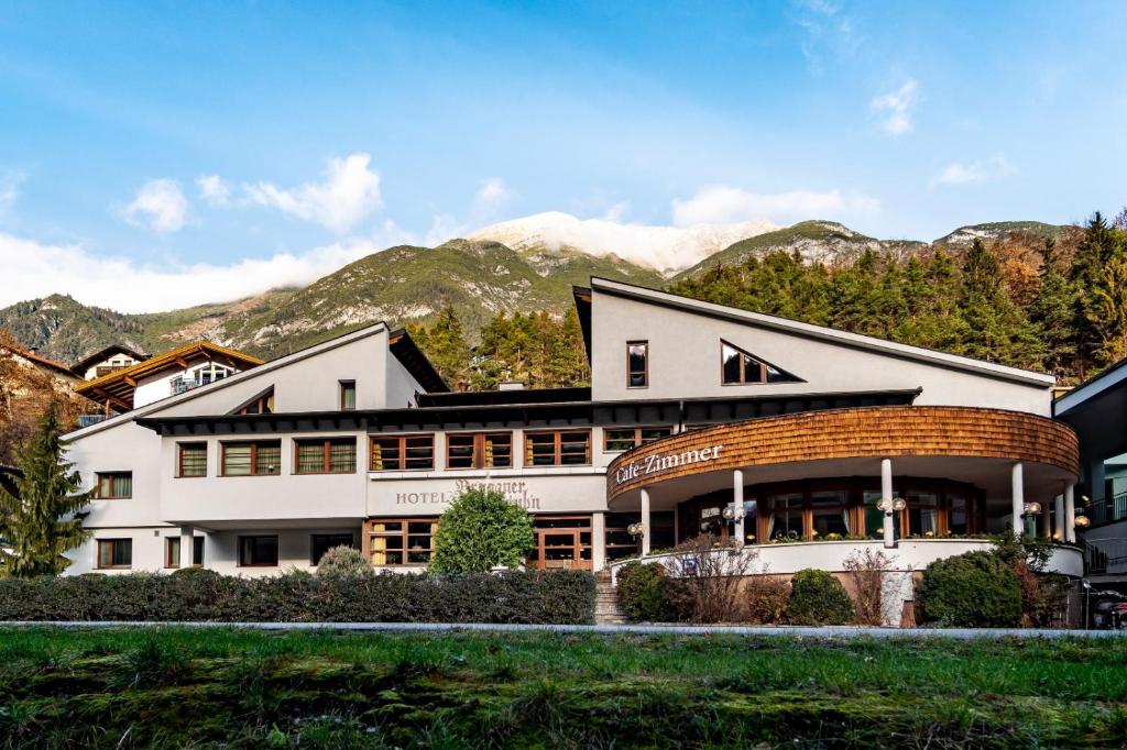 a large white building with mountains in the background at Hotel Bruggner Stub`n in Landeck