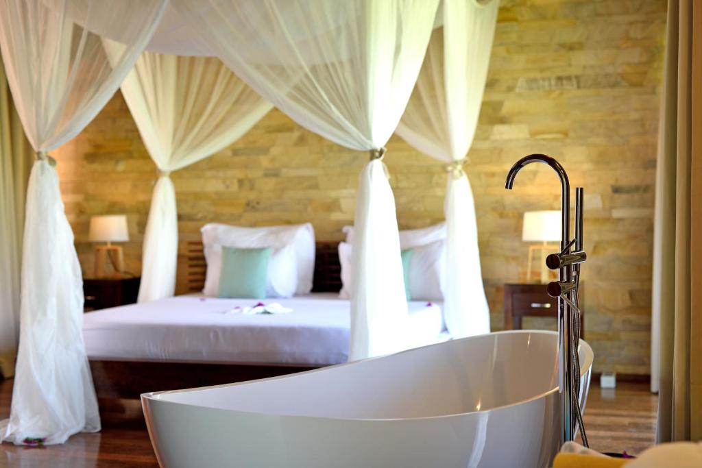 a bath tub in a bedroom with a bed at Tulia Zanzibar Unique Beach Resort in Pongwe