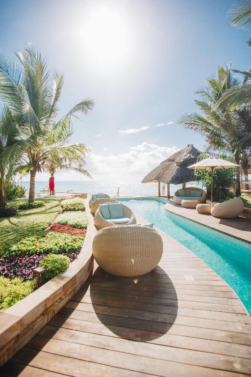 a swimming pool with lounge chairs and the ocean at Tulia Zanzibar Unique Beach Resort in Pongwe