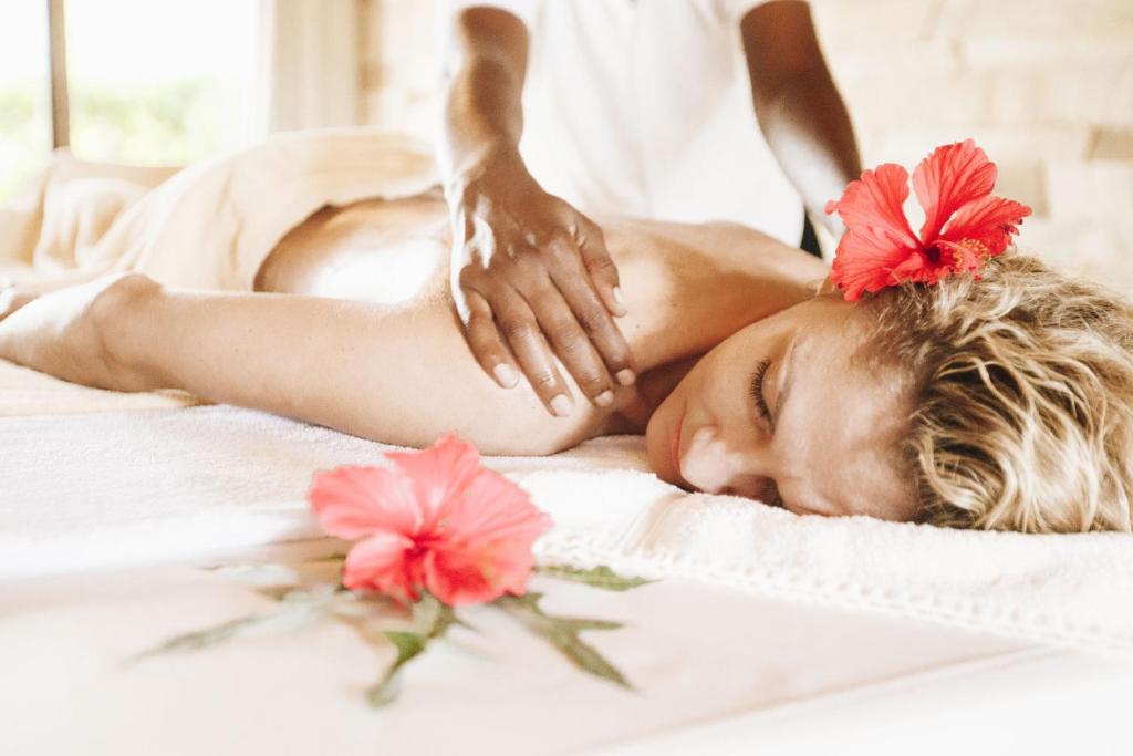 a woman getting a massage in a spa with flowers at Tulia Zanzibar Unique Beach Resort in Pongwe