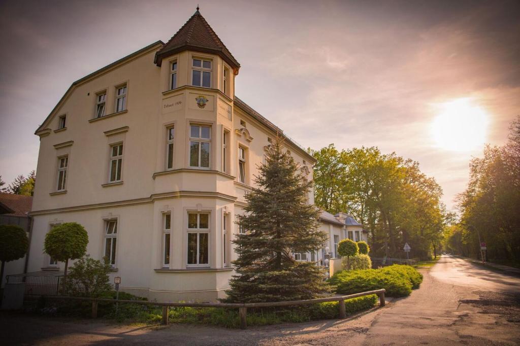 ein weißes Gebäude mit einem Uhrturm darüber in der Unterkunft Hotel & Restaurant Waldschlösschen in Kyritz