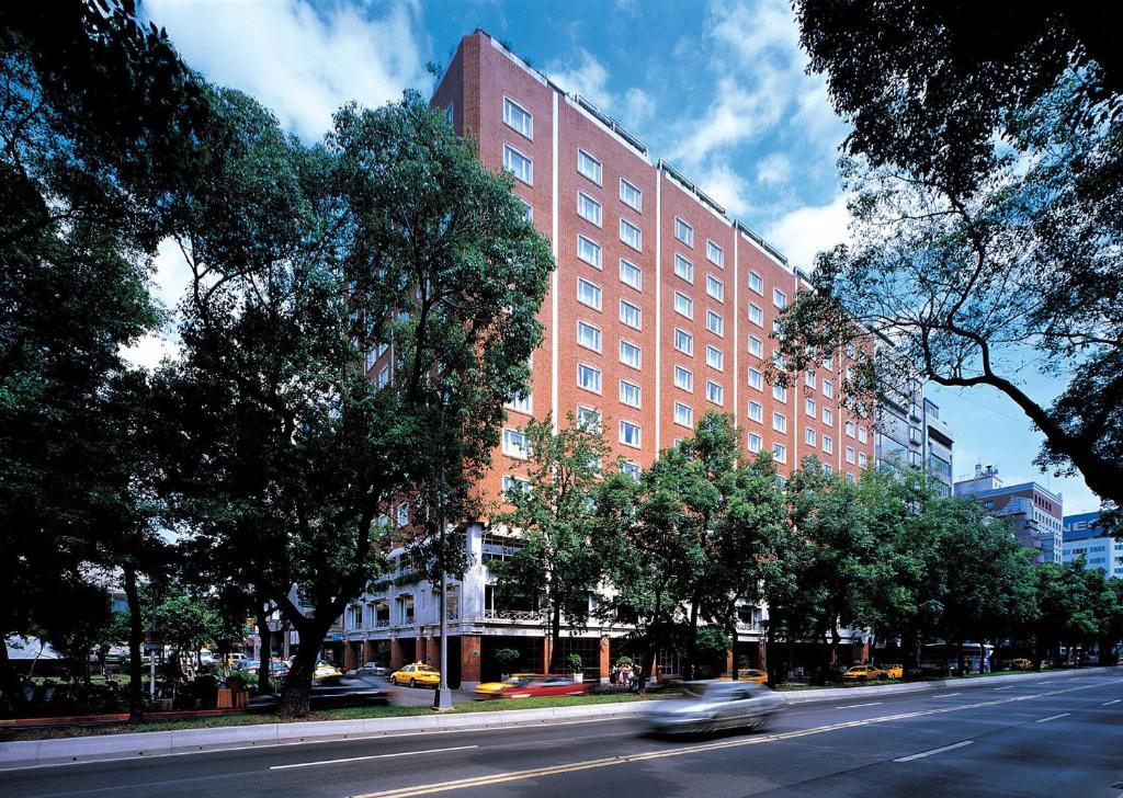 een auto die door een straat rijdt voor een gebouw bij Hotel Royal-Nikko Taipei in Taipei