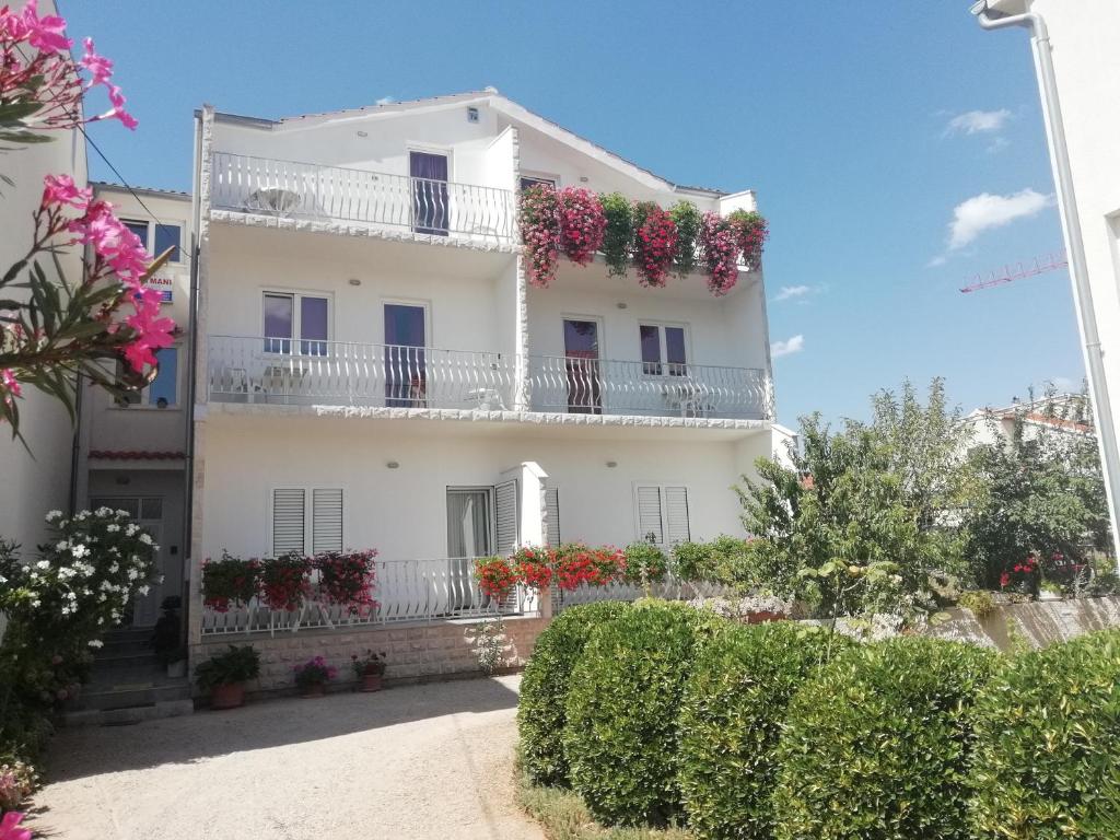 a white house with flowers on the balconies at Apartments Vidović in Vodice