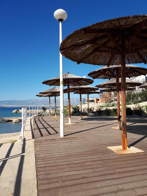 a wooden boardwalk with umbrellas on the beach at Apartment Aquamarine in Vir