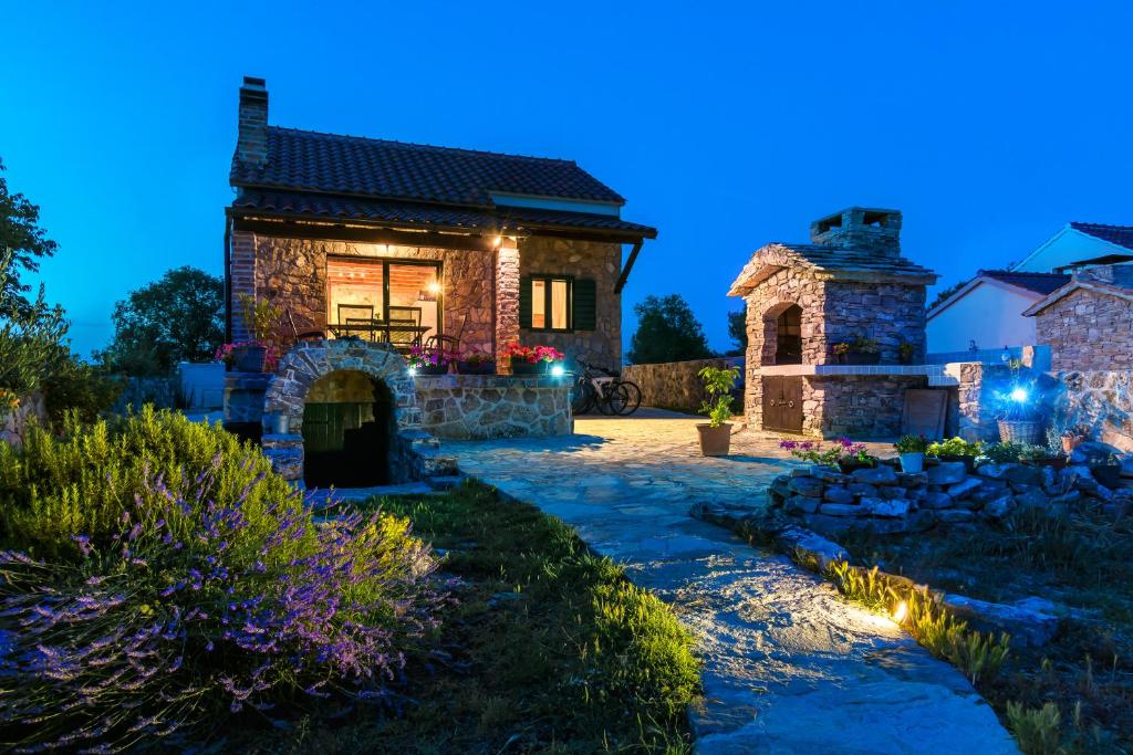 uma casa de pedra com uma lareira de pedra num quintal em Holiday Home Vlatka em Lozovac