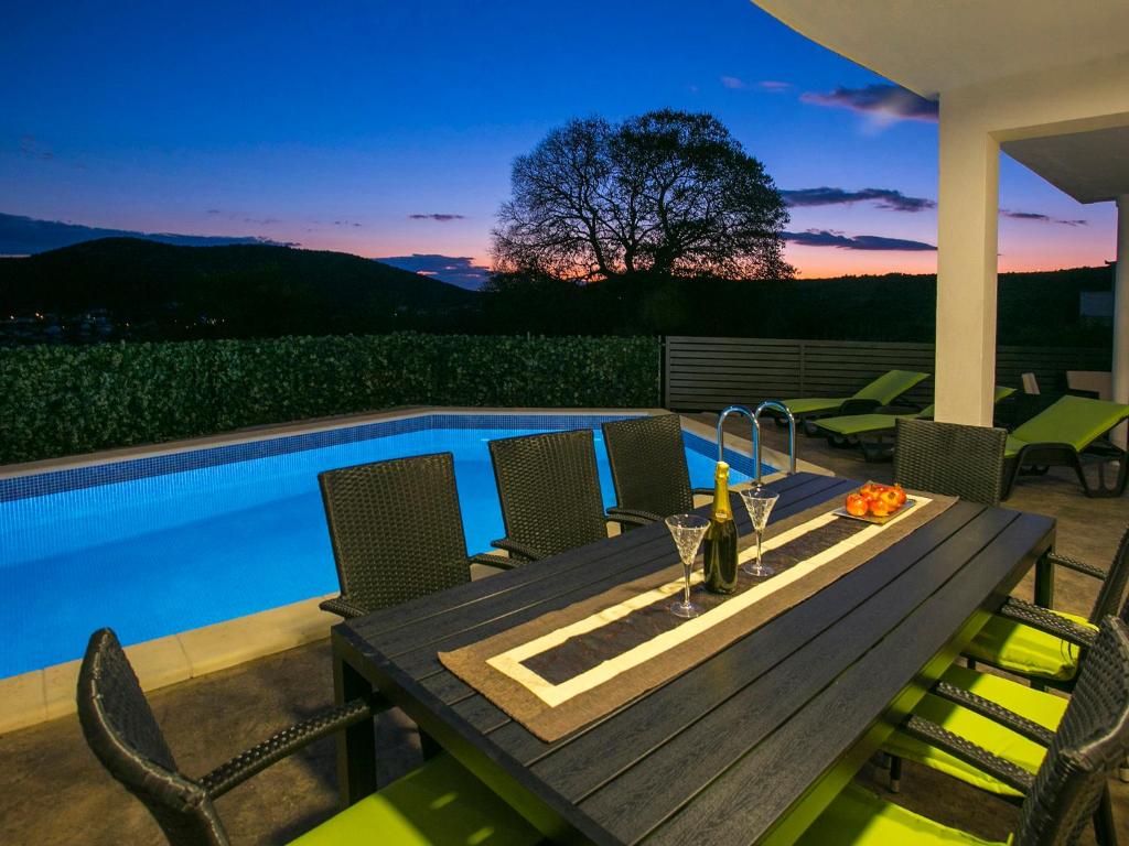 - une table et des chaises en bois à côté de la piscine dans l'établissement Villa Croatia Sea View with heated pool, à Vinišće