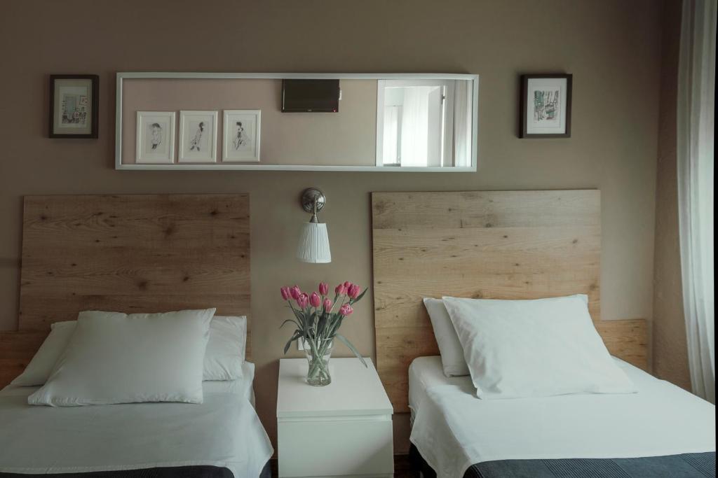 a bedroom with two beds and a vase of flowers at B&B Inés in Sant Cugat del Vallès