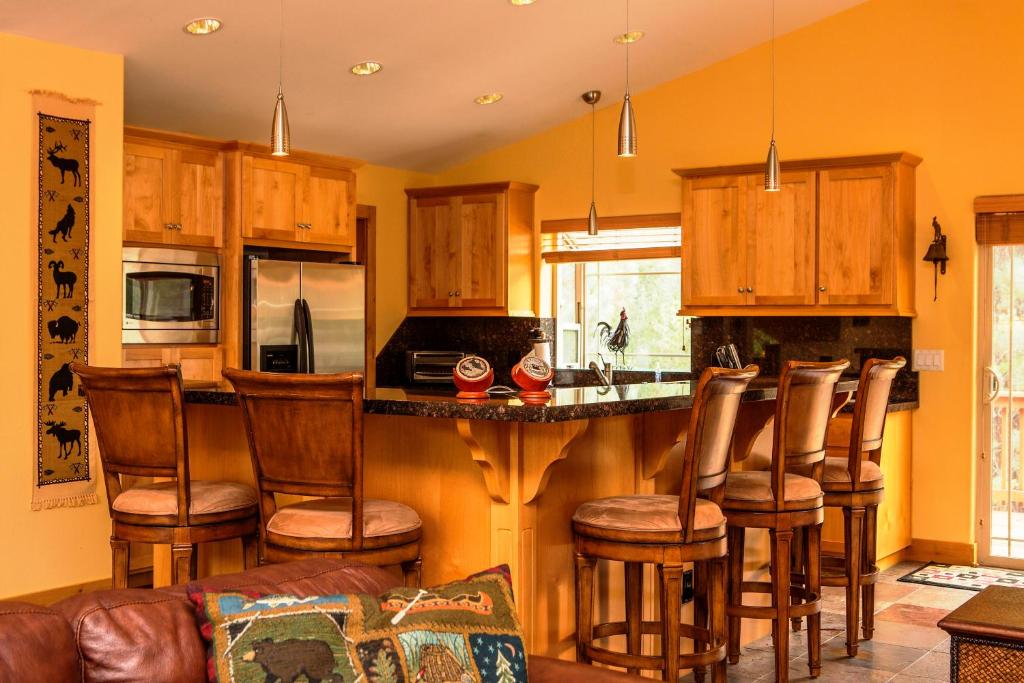 una cocina con armarios de madera y un bar con taburetes en 5-Star Luxury Tahoe Cabin! Great Location! Pool Table!Darts! Poker! Ping Pong! Games!, en South Lake Tahoe