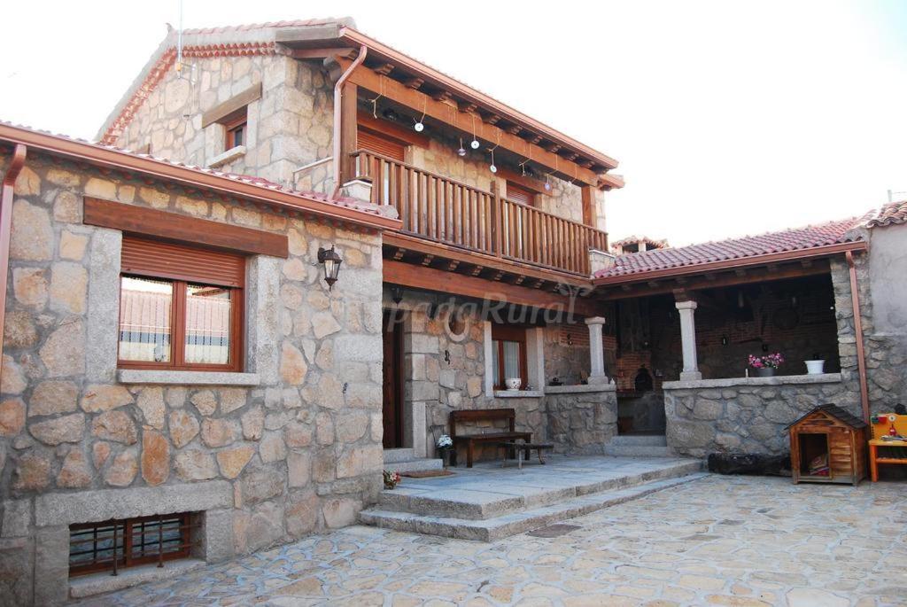 a stone house with a balcony and a patio at casa rural La Gabina in Muñogalindo