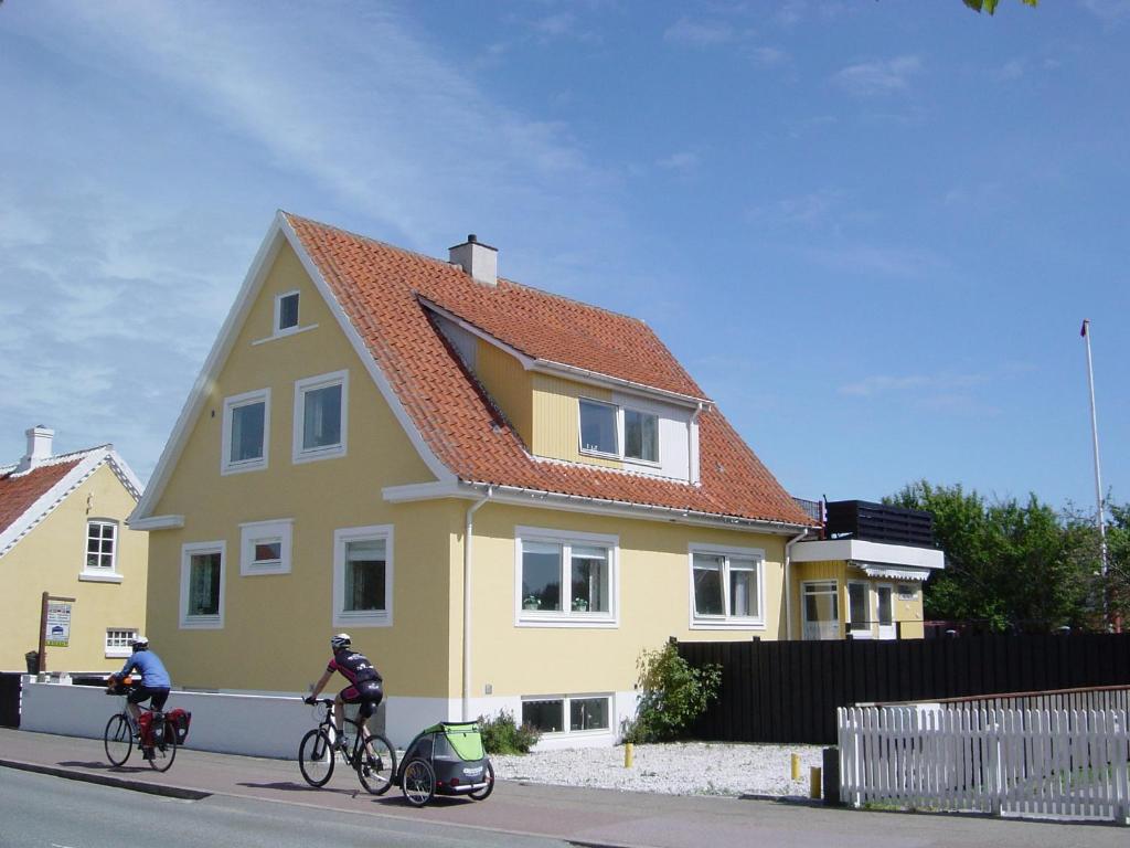 duas pessoas a andar de bicicleta em frente a uma casa amarela em Oddevej 20 Skagen em Skagen