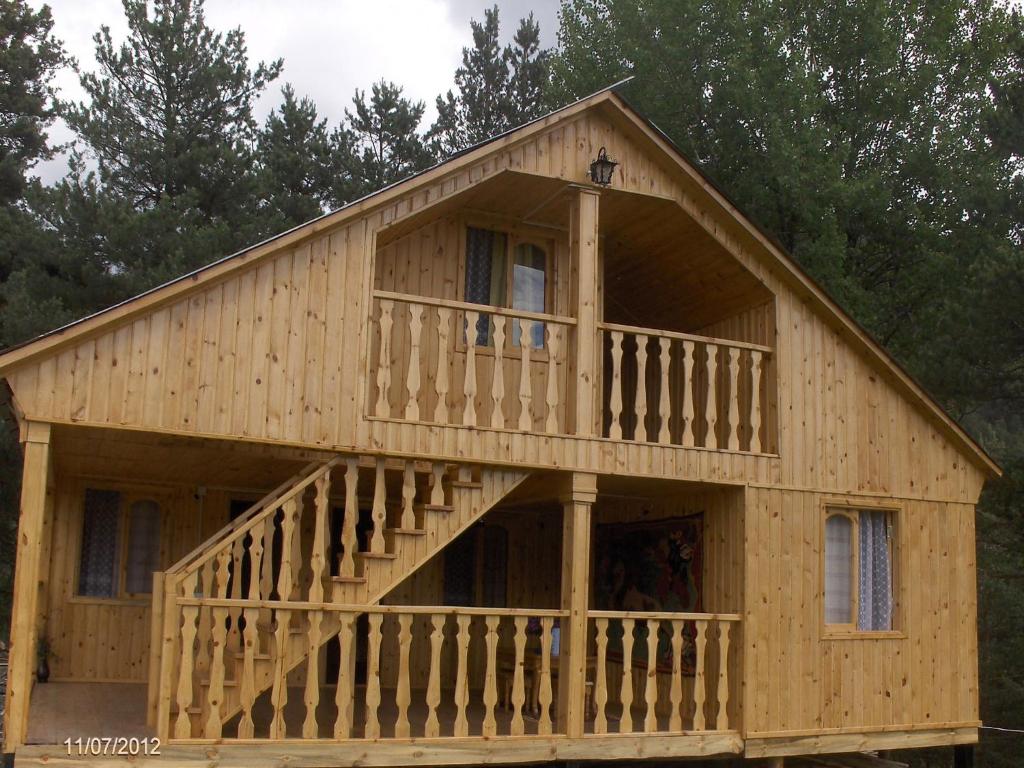 a large wooden house with a large deck at Guest House Mirgvela in Omalo