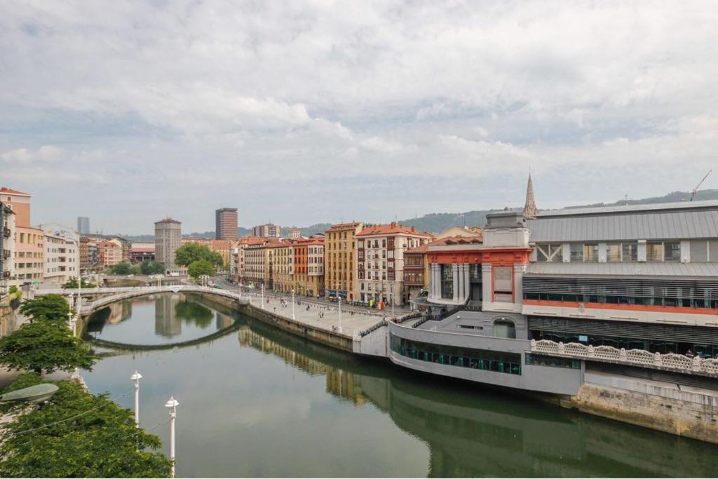 a river in a city with buildings and a bridge at Martzana Kalea in Bilbao
