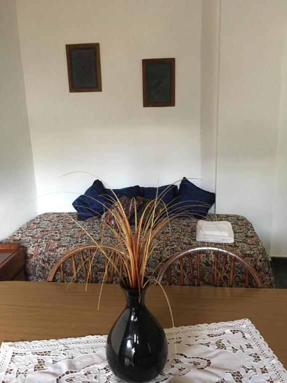 eine schwarze Vase auf einem Tisch vor einem Bett in der Unterkunft Departamento Belgrano in San Pedro