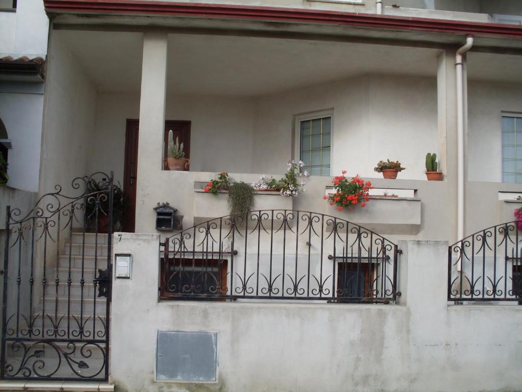 una casa bianca con piante in vaso sul balcone di Affittacamere Peonia a Oliena