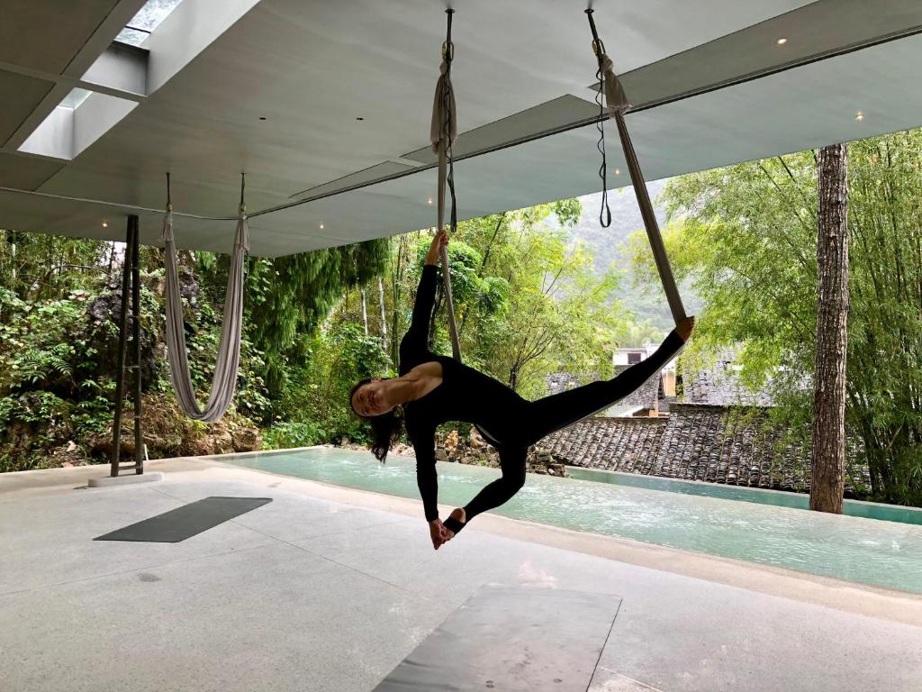 a woman is on a rope swing by a pool at XY·Yun House in Yangshuo