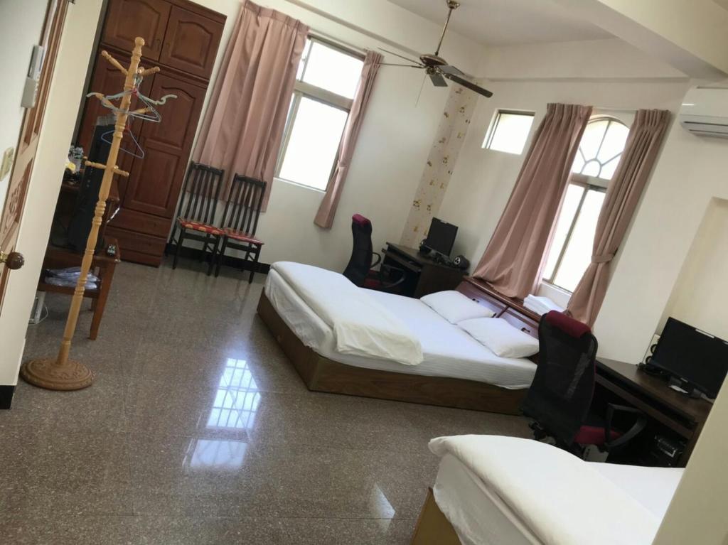 a room with two beds and a desk and windows at Xiao Jinmen Homestay in Lieyu