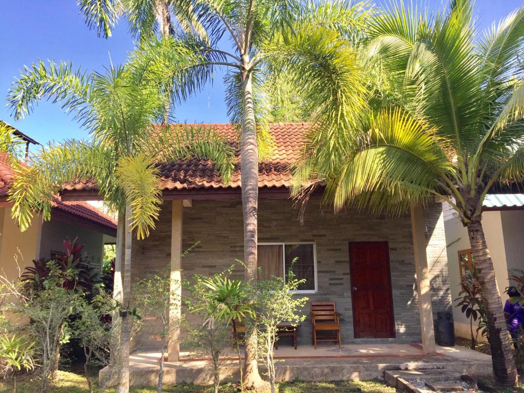 una casa con palmeras delante en Coconut Bungalow, en Nai Yang Beach