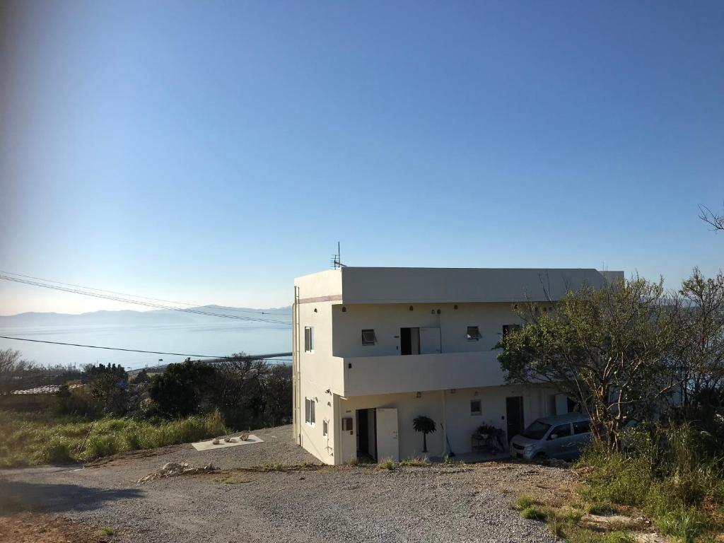 un edificio blanco con un coche aparcado delante de él en シーブリーズ古宇利, en Nakijin