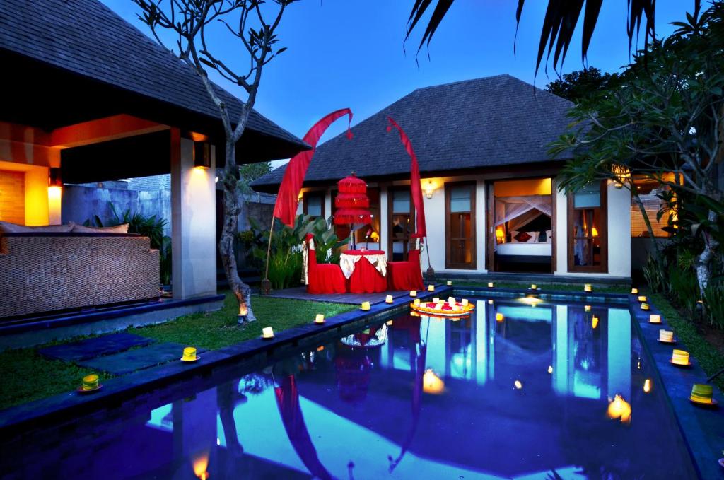 a swimming pool in front of a house at night at The Khayangan Dreams Villa Umalas in Seminyak