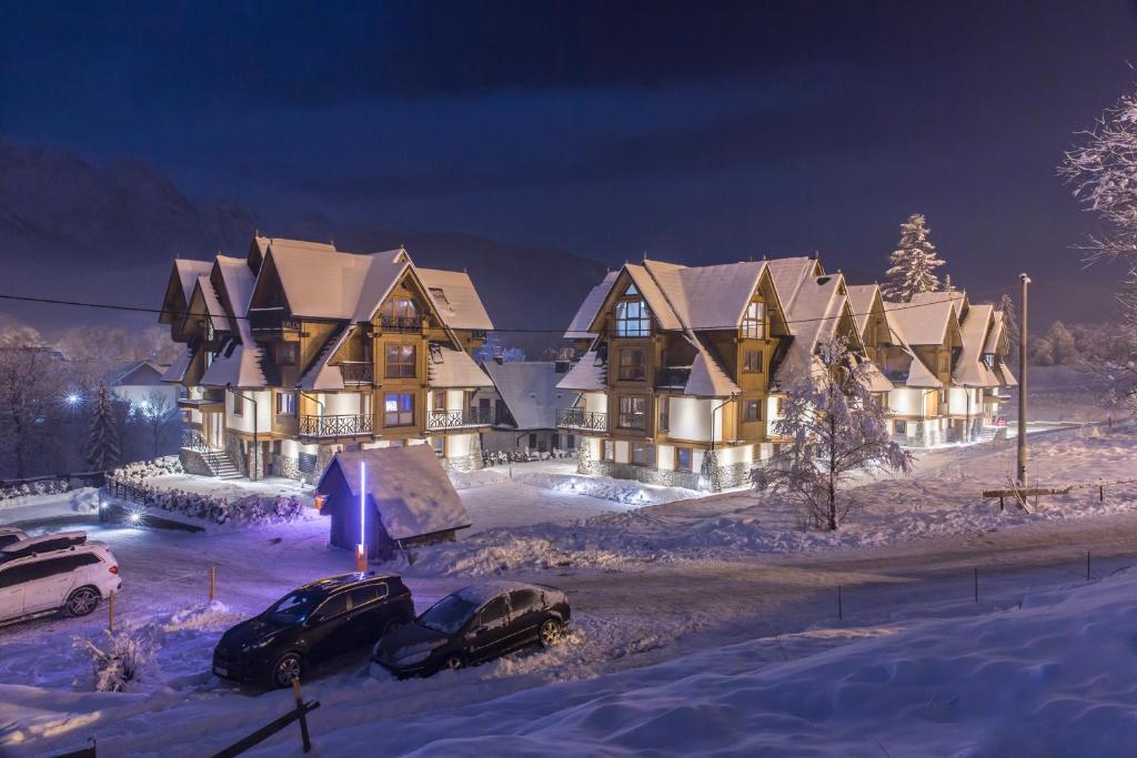 a house with cars parked in the snow at night at Polana Szymoszkowa Ski Resort in Zakopane