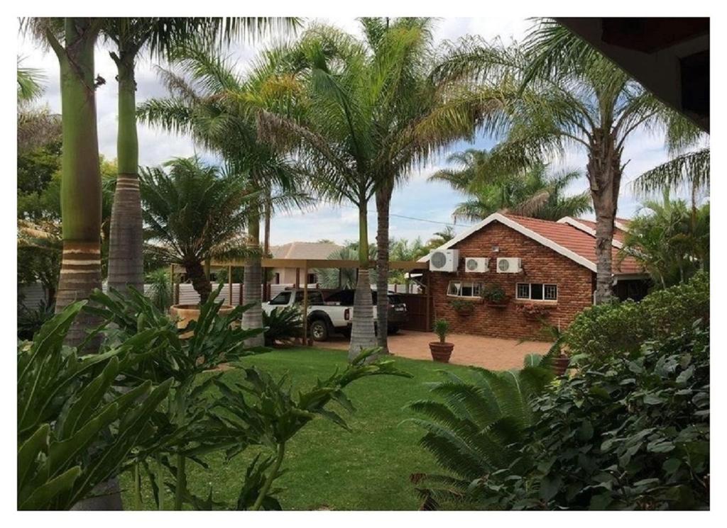 a house with palm trees and a truck in the yard at Lala Bela Guest House in Bela-Bela