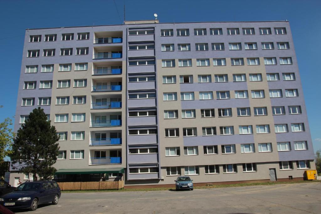 un gran edificio de apartamentos con un coche aparcado delante de él en City Building, en Šaca