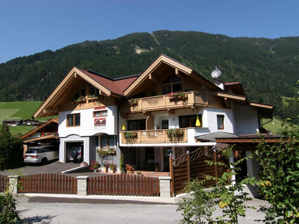 ein großes Haus mit einem Berg im Hintergrund in der Unterkunft Appartements Enzian in Finkenberg