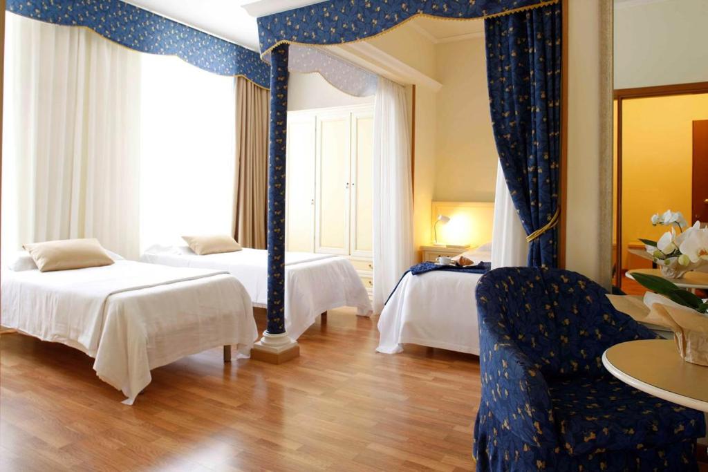 a hotel room with two beds and a blue chair at Residence Liberty in Trieste
