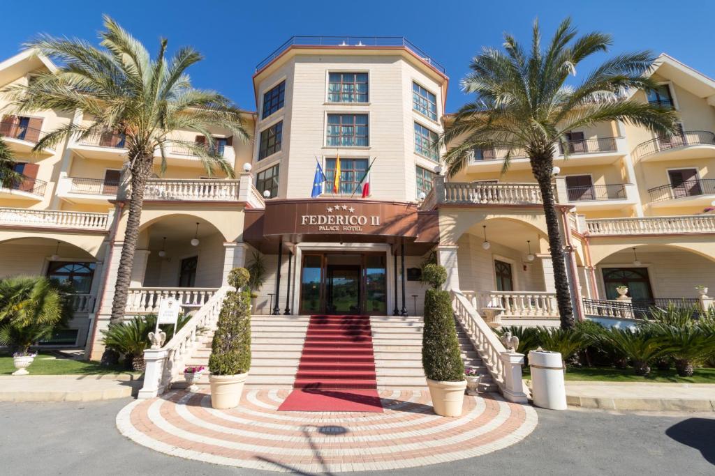 a building with palm trees in front of it at Hotel Federico II in Enna