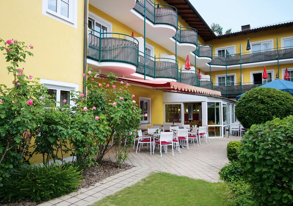 un patio avec des tables et des chaises en face d'un bâtiment dans l'établissement Hotel Promenade, à Bad Füssing