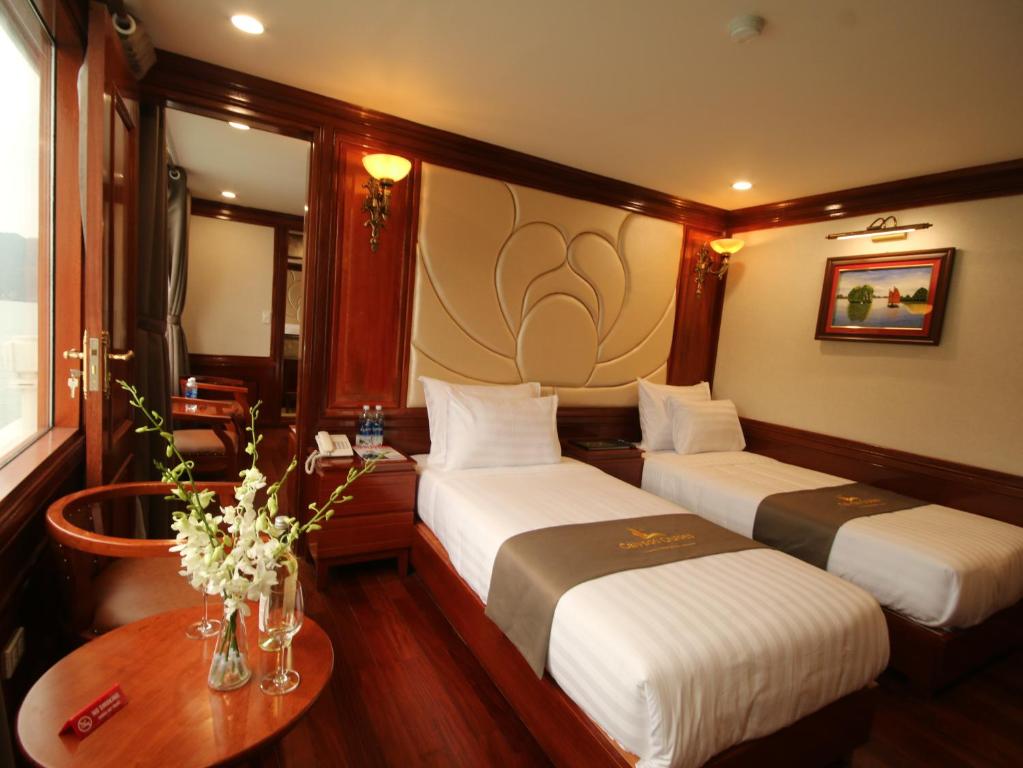 a bedroom with two beds and a table with flowers at Calypso Cruises in Ha Long
