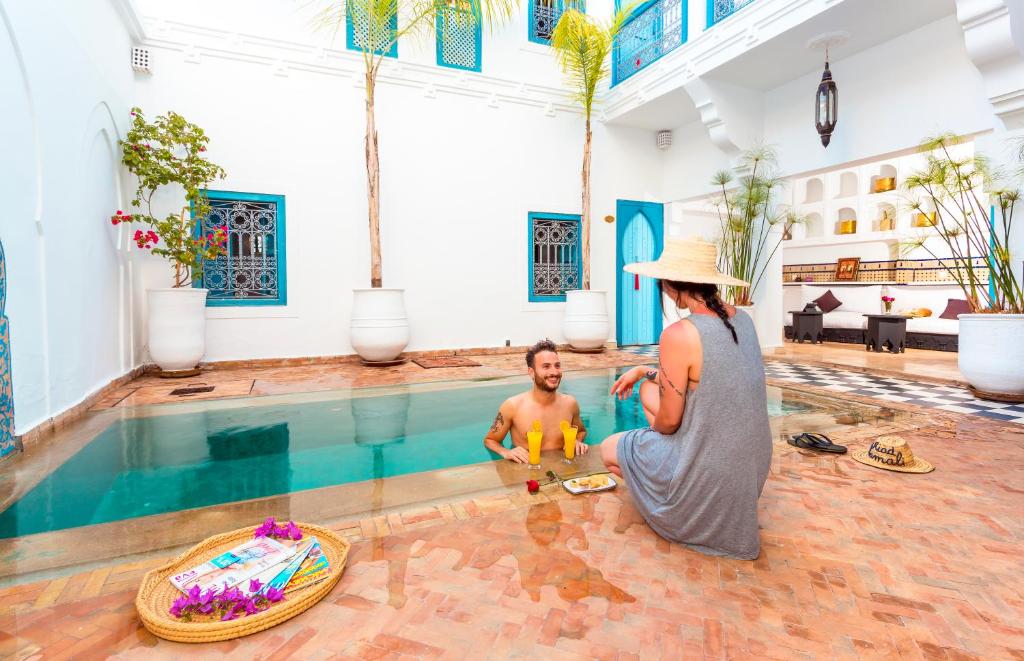 a woman standing next to a man in a swimming pool at Riad Chamali in Marrakesh