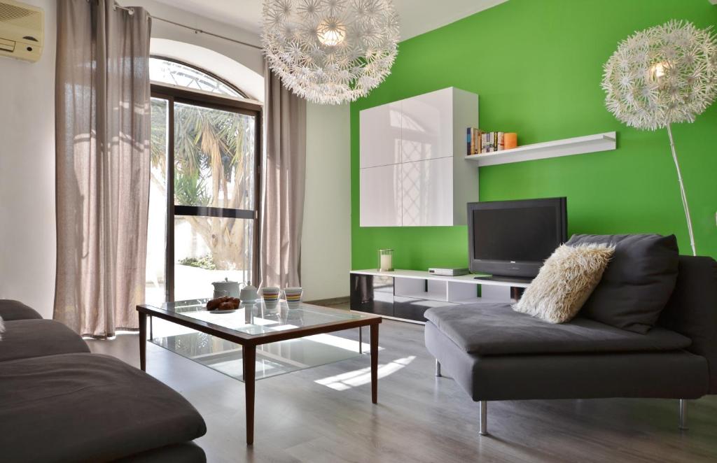 een groene woonkamer met een bank en een tv bij City Living Suites TK1 Rm 2 in St Julian's