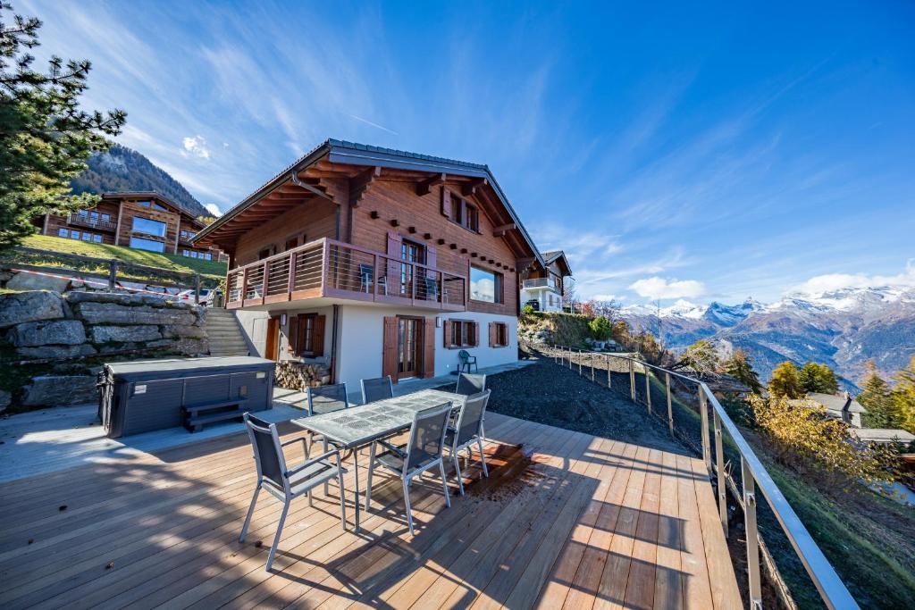 a house with a table and chairs on a deck at Chalet Riquet - Ski/in-out - Jacuzzi in Nendaz