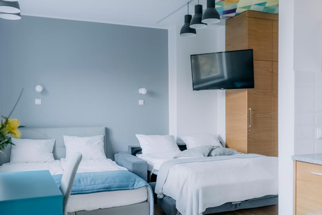 a room with three beds and a flat screen tv at APARTEL Plac Zbawiciela Studio in Warsaw