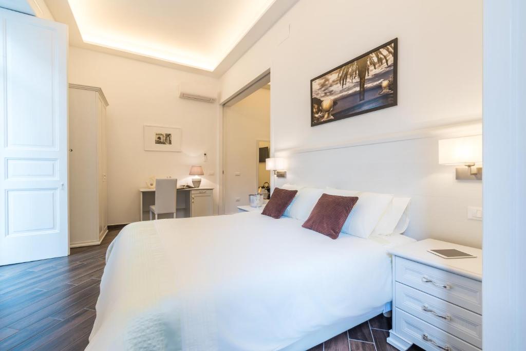 - une chambre avec un grand lit blanc et un bureau dans l'établissement Suites Sorrento Elegance, à Sorrente