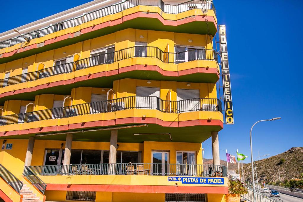 un edificio amarillo con balcones en un lateral en Hotel Iberico en Castell de Ferro