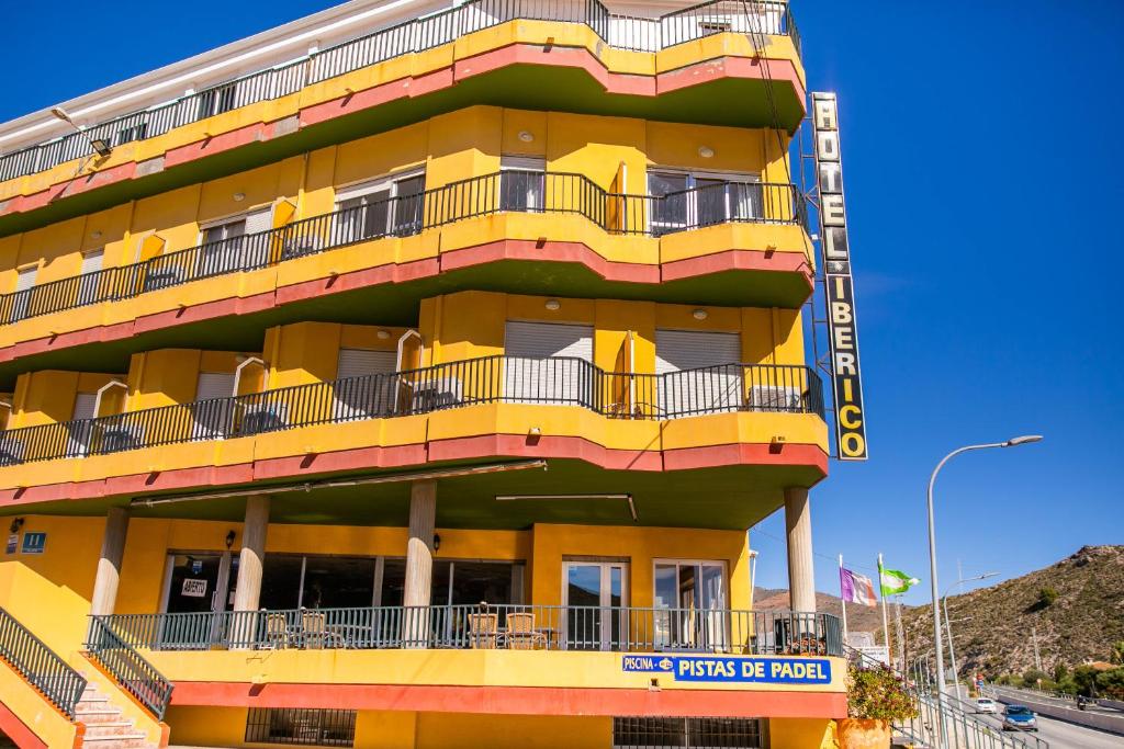 un bâtiment jaune avec des balcons sur son côté dans l'établissement Hotel Iberico, à Castell de Ferro