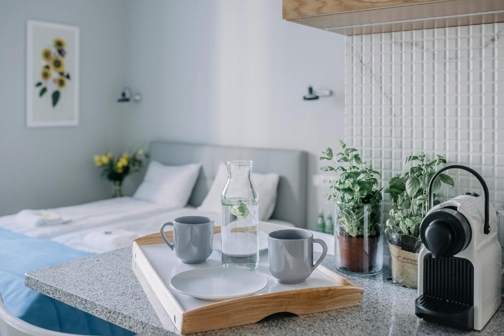 einen Tisch mit einem Tablett mit Tassen und einer Flasche Wasser in der Unterkunft APARTEL Plac Unii Lubelskiej Studio in Warschau