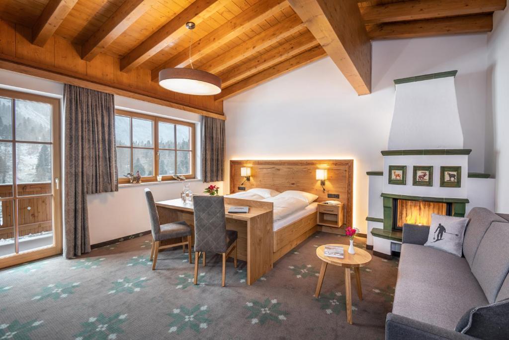 a bedroom with a bed and a desk and a fireplace at Aparthotel Weningeralm in Obertauern