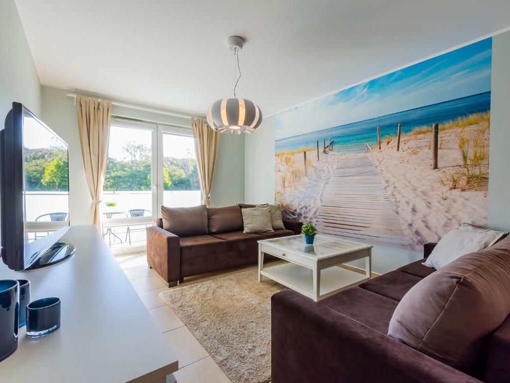 - un salon avec un canapé et une peinture sur la plage dans l'établissement VacationClub - Aquarius Apartament 93, à Kołobrzeg