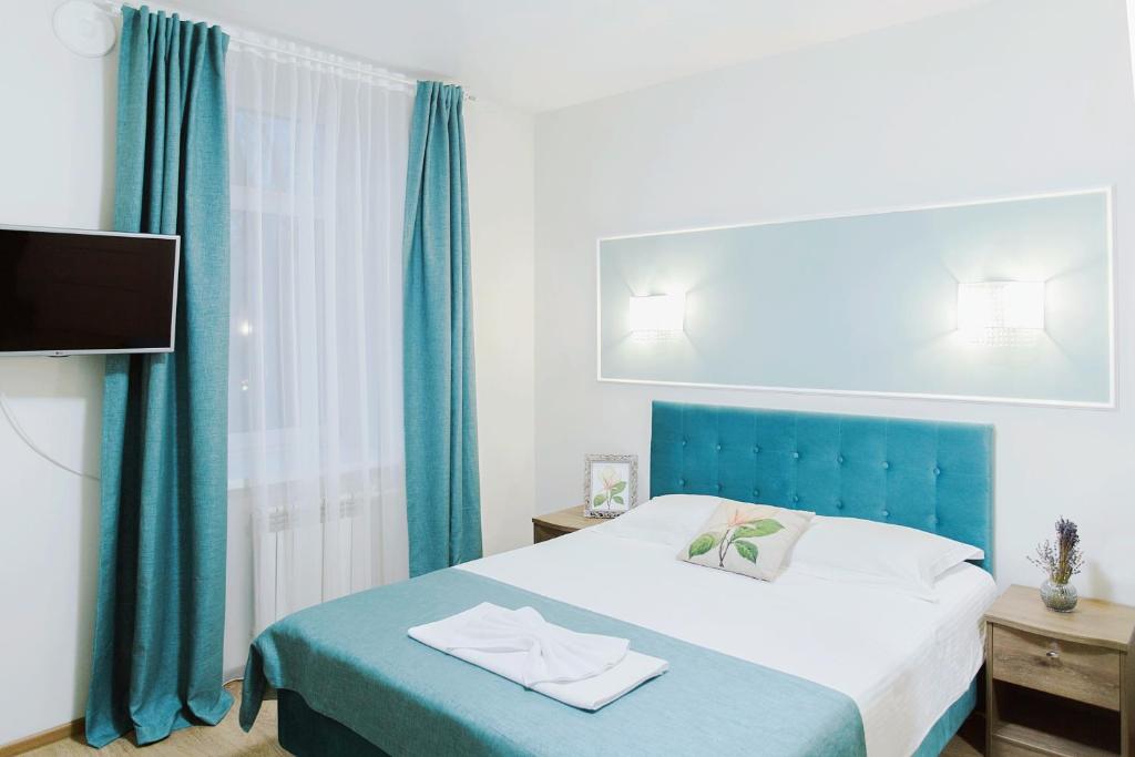 モスクワにあるファルファレル ホテルのベッドルーム(ブルーヘッドボード付きのベッド1台、テレビ付)