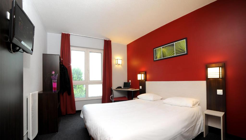 Habitación de hotel con cama y pared roja en HOTEL l'EAUBONNE en Eaubonne
