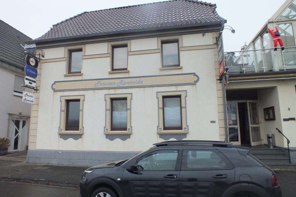 a black car parked in front of a building at Pension Riverside in Leverkusen Hitdorf am Rhein - Zentral an der A1 und 59 in Leverkusen