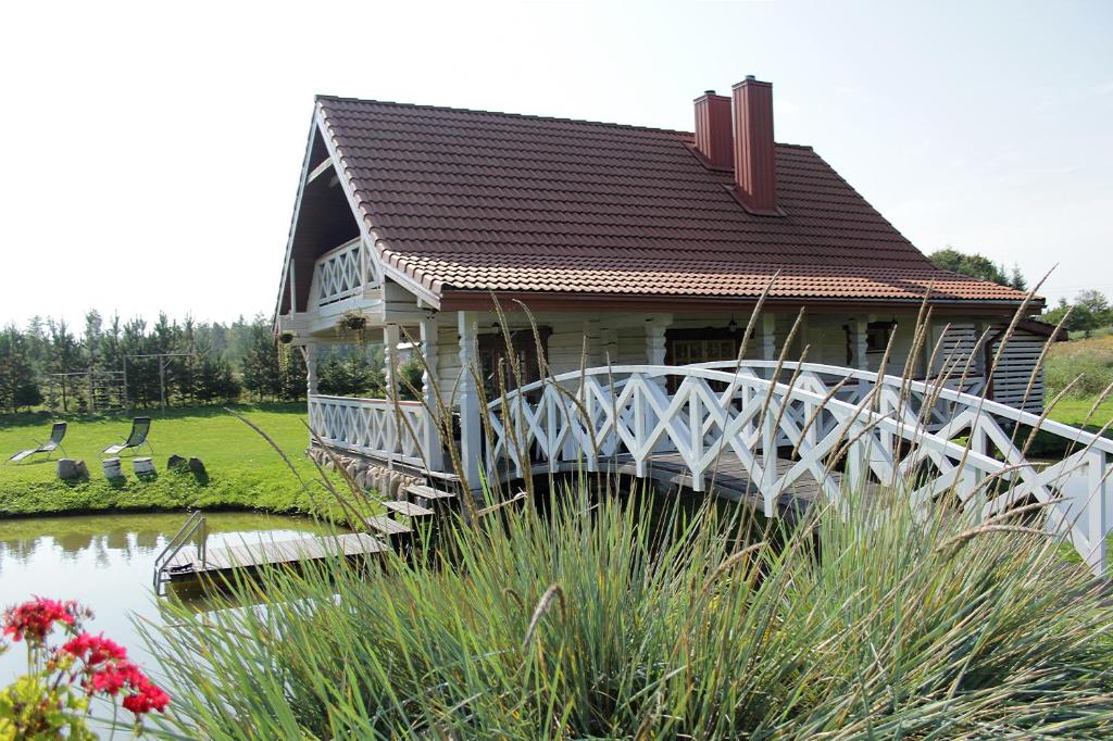 uma pequena casa com uma ponte sobre um lago em Sodyba pas Olgą em Mickūnai