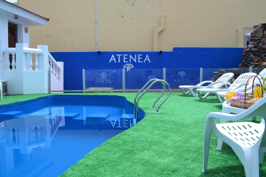 una piscina con césped junto a una pared azul en Atenea en Villa Carlos Paz
