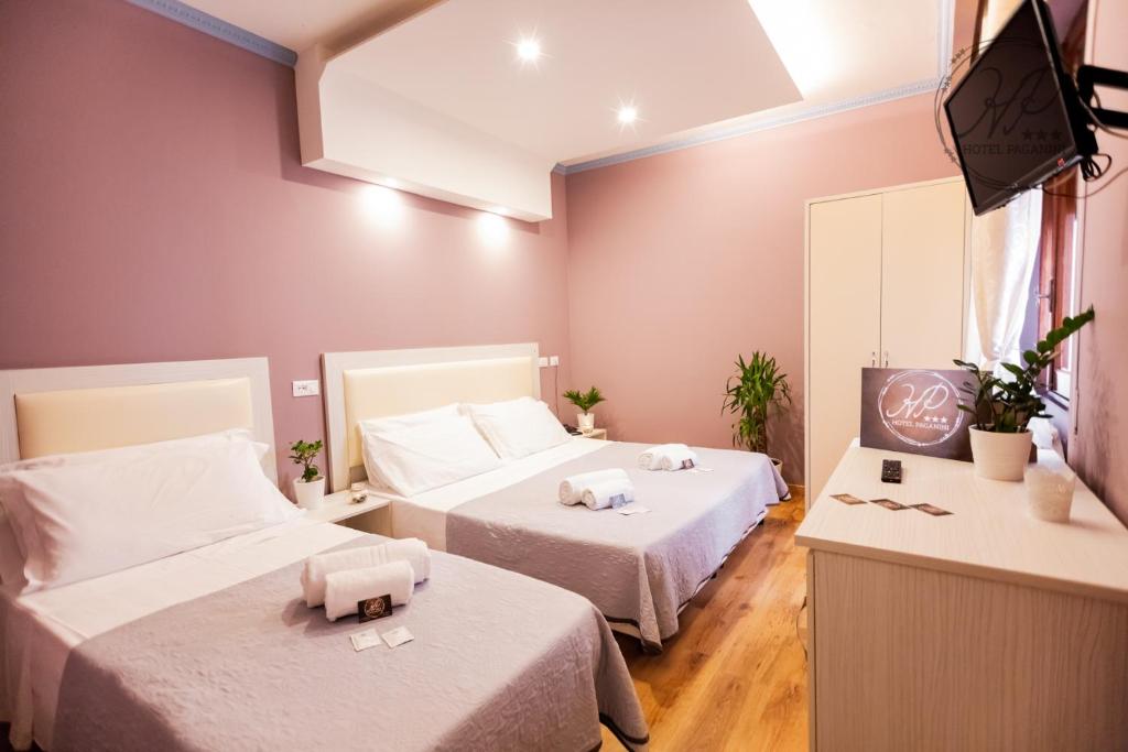 una camera d'albergo con due letti e una televisione di Hotel Paganini a Firenze