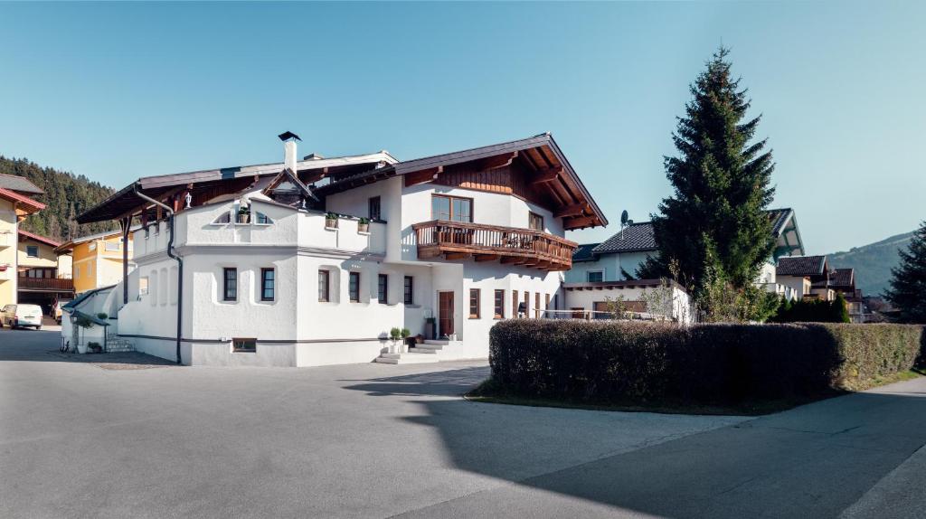 a white house with a wooden roof on a street at Die feine Herberge in Altenmarkt im Pongau